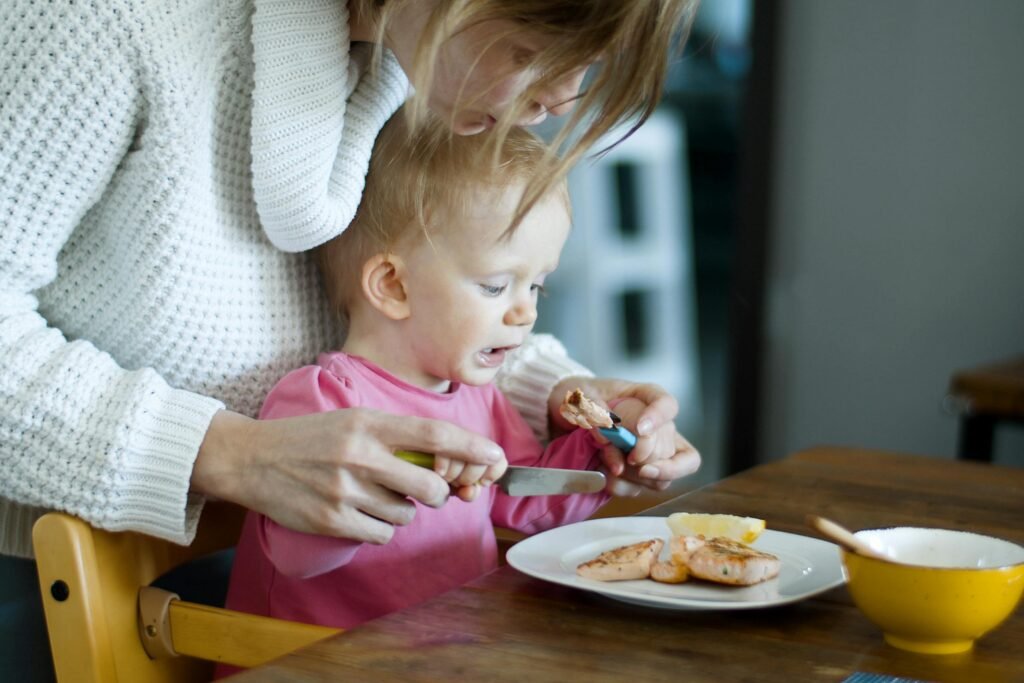 Niño en la mesa mirando hacia otro lado mientras sus padres lo presionan para comer